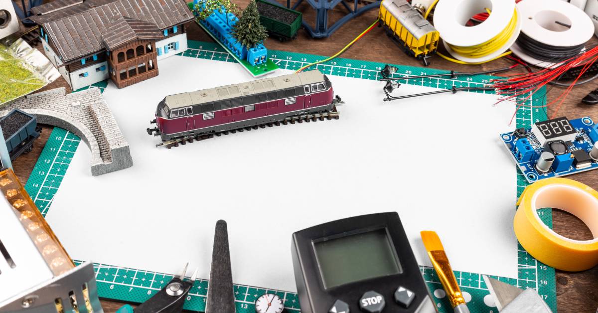 A mat with multiple different kinds of model railway equipment sitting on it, including a train and wires.